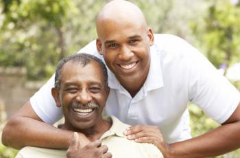 Young African American man embracing older man. 