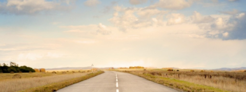 An image of an open, rural road with a blue sky background