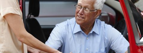 woman helping man out of a car