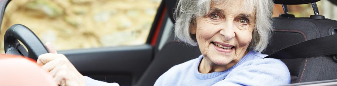 Older Woman driving a red car. 